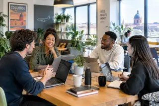 Groupe de jeunes entrepreneurs travaillant ensemble autour d’une table dans un espace de coworking lumineux à Toulouse, ambiance collaborative et professionnelle.